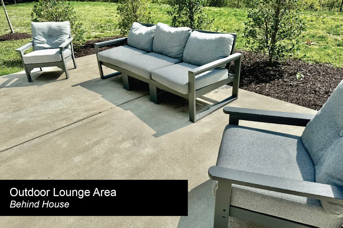 An inviting outdoor lounge area with comfortable seating, a lush green lawn, and surrounding bushes. The setup encourages relaxation, socializing, and enjoying fresh air—perfect for unwinding after work or informal meetings.