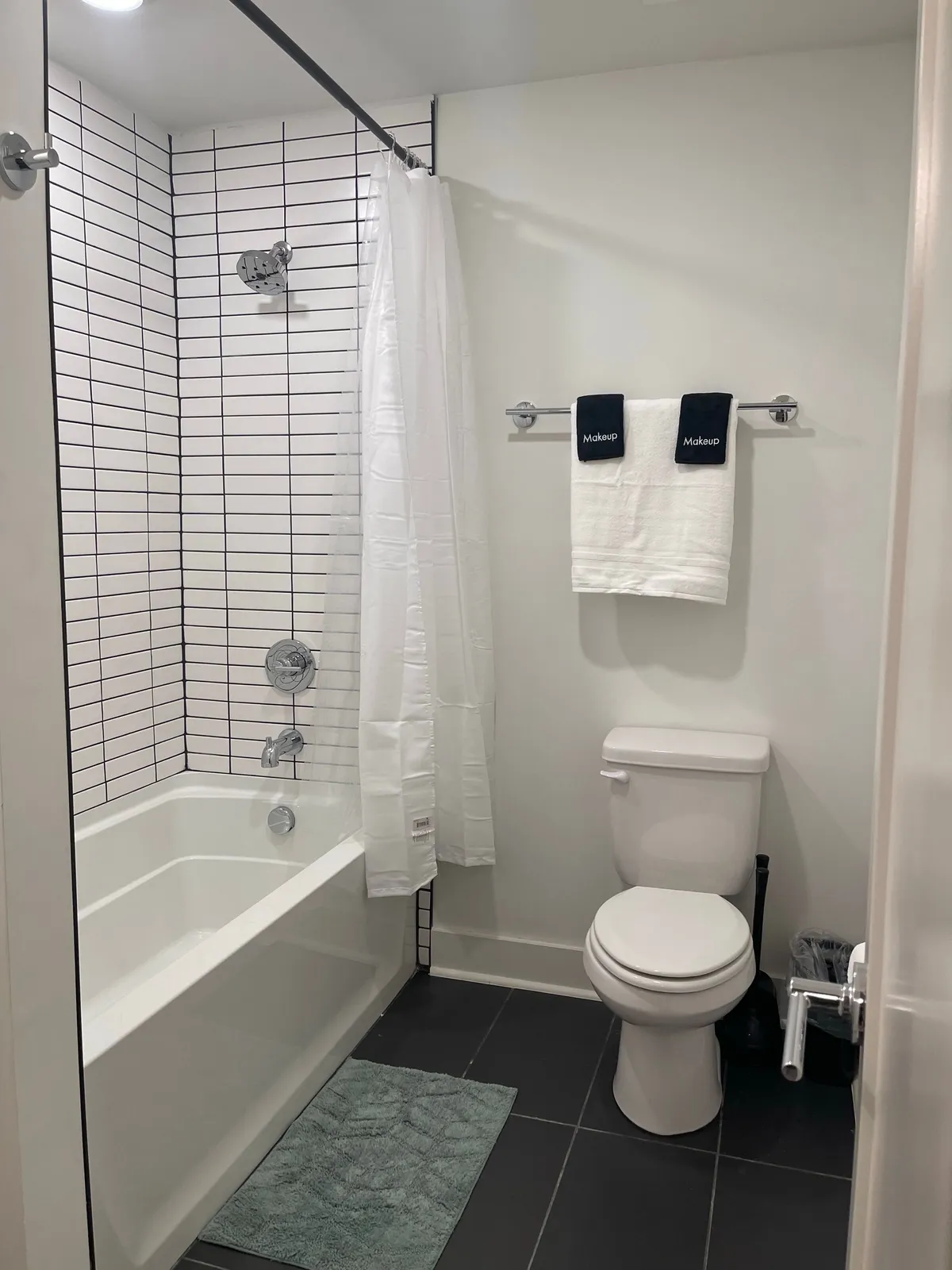 A bathroom with a bathtub, white shower curtain, towels, and a toilet. The space is clean, inviting, and clearly designed for comfort and rejuvenation, echoing the 'spa-like' and 'refreshing' experience described in the section.